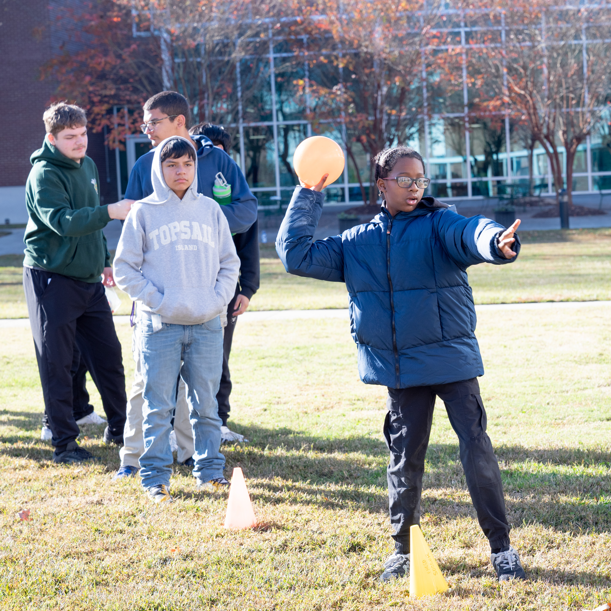 Fall Fest: Student with arm cocked to trow ball at bucket pyramid