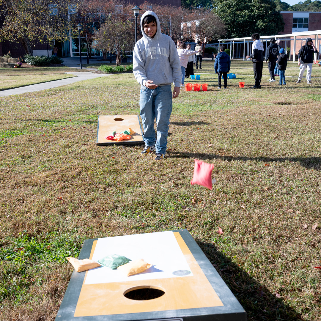 Fall Fest: Student throwing bean bag at corn hole board