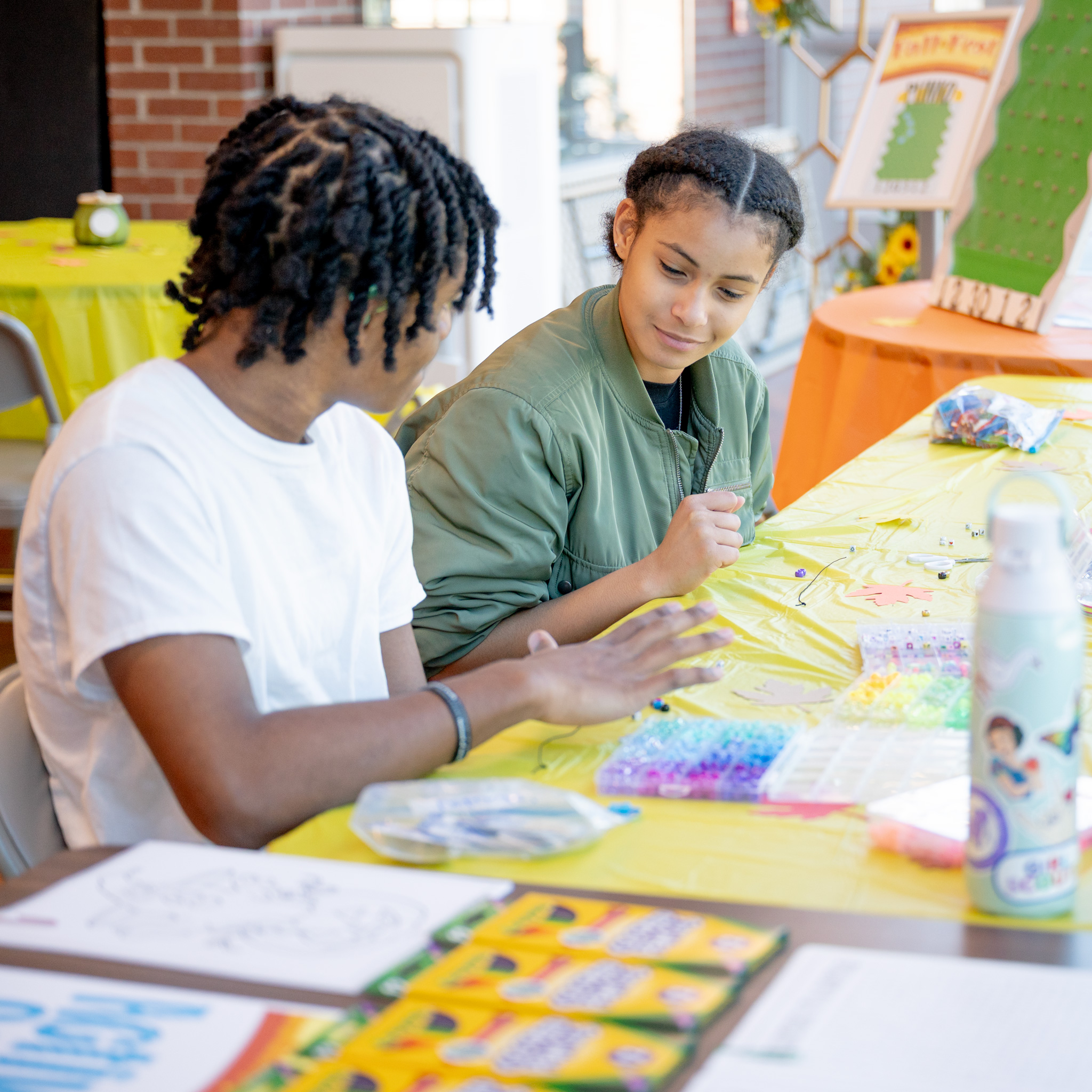 Fall Fest: Two students making bracelets with colorful beads at the Activity Center