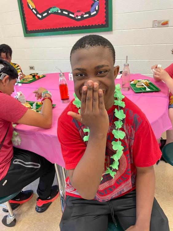 Student wearing lei covering his mouth