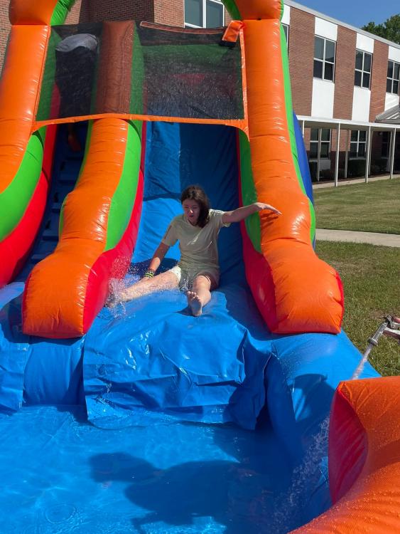Student sliding down inflated water slide