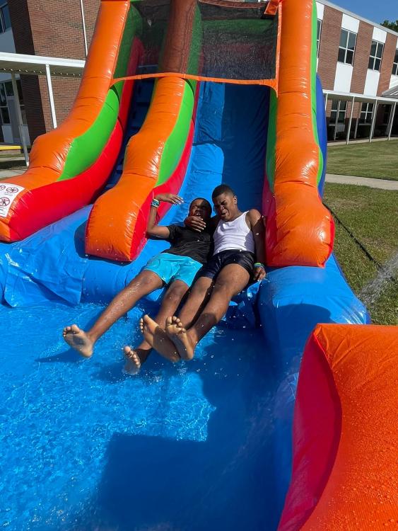Students sliding down inflated water slide together