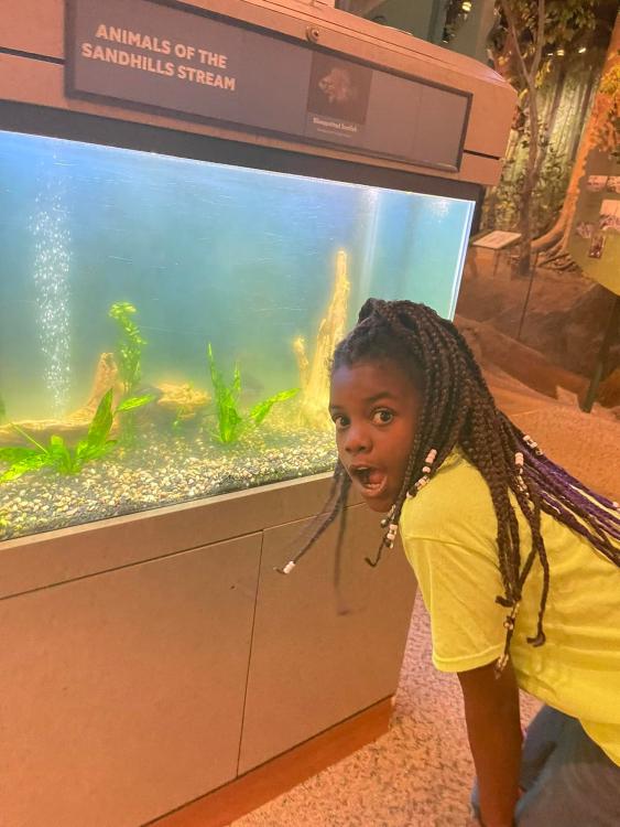 Student at the NC Museum of Natural Sciences in front of an aquarium