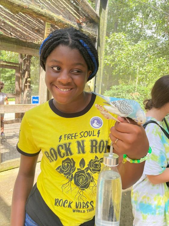 Smiling student holds parakeet perched on her hand