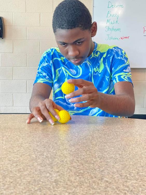 Student trying to stack two plastic golf balls
