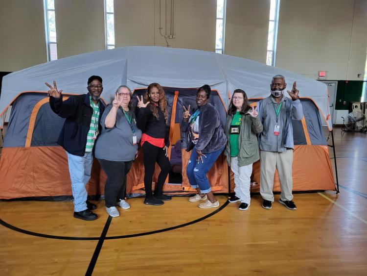 Staff posing in front of a tent in the gym