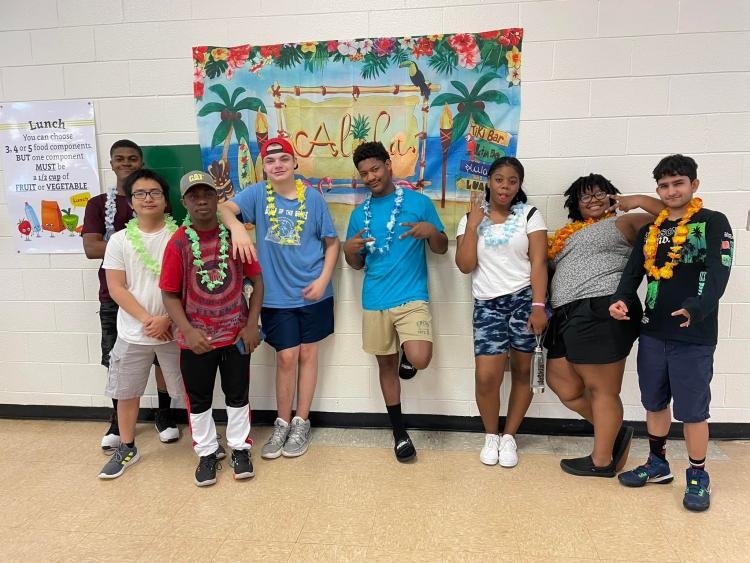 Students wearing leis in front of 'aloha' poster