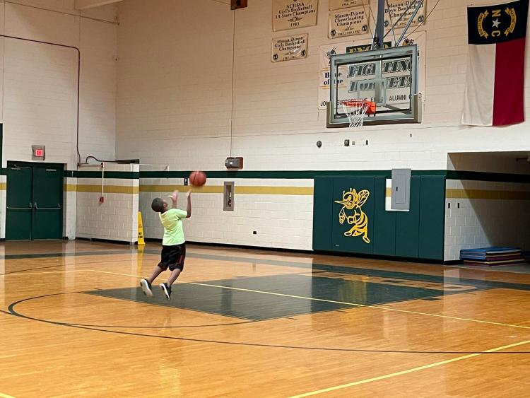 Student shooting a basket ball in the gym
