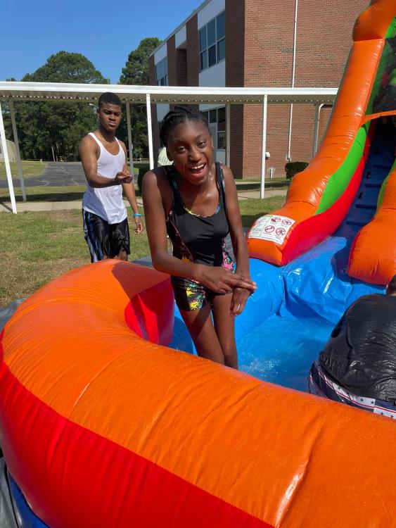 Student in inflated water slide soaked and smiling