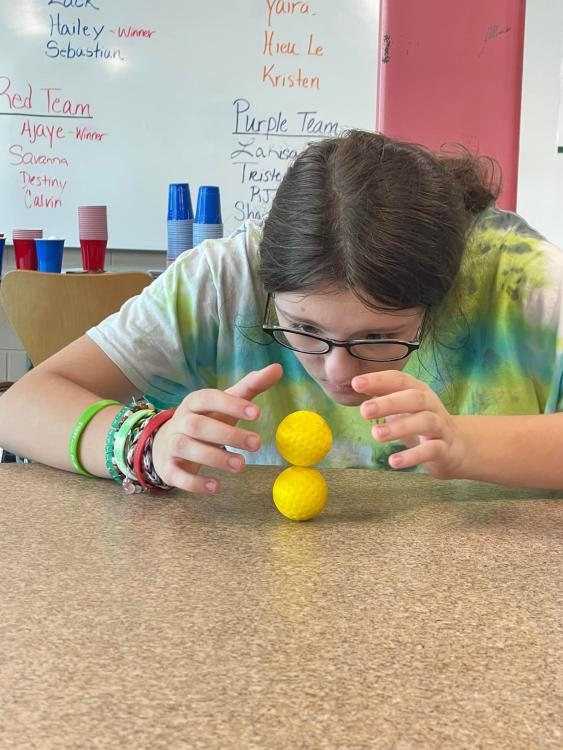 Student trying to stack two plastic golf balls