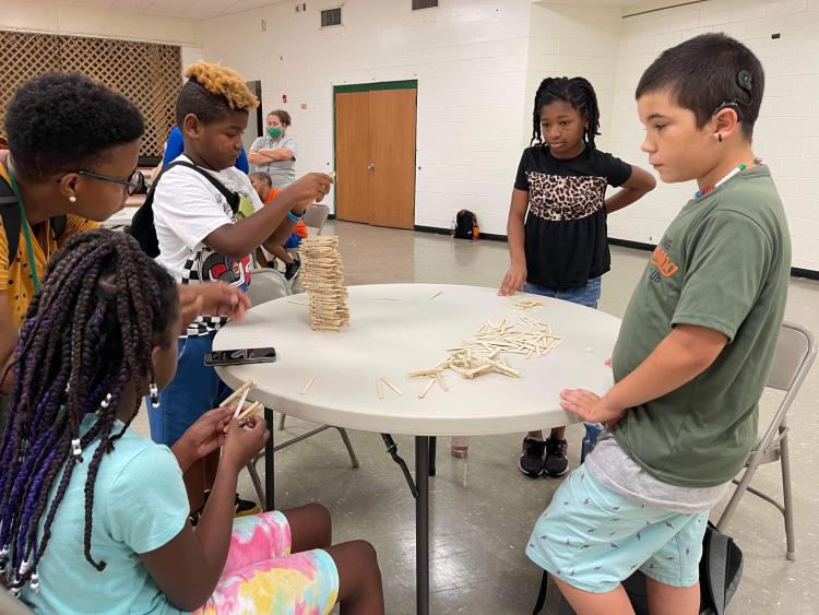 students stacking sticks in log house pattern