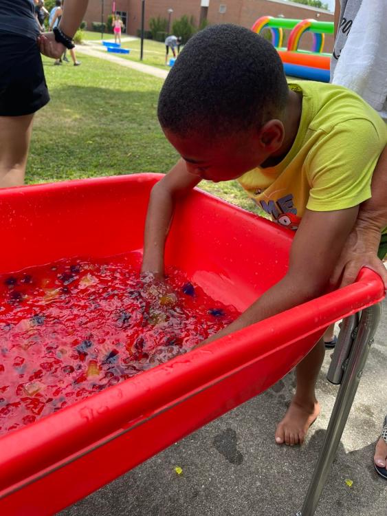 student with hands in colorful tub of gelatin