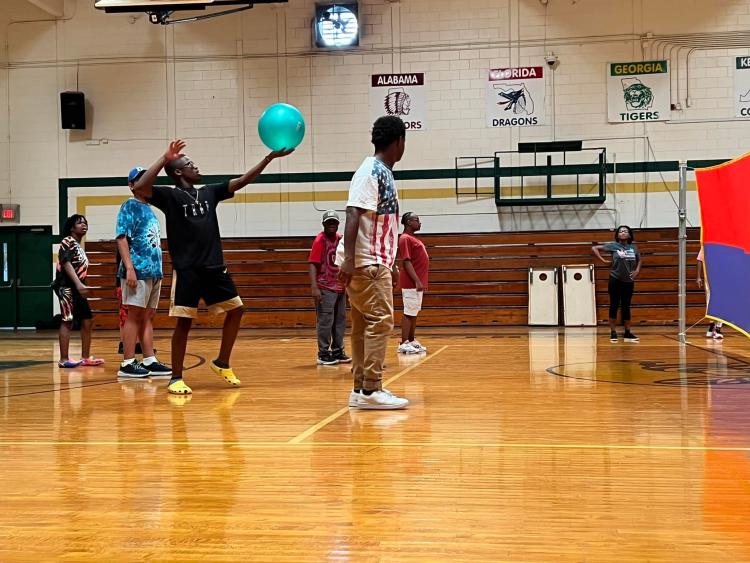 A student serves in a game of blind volleyball