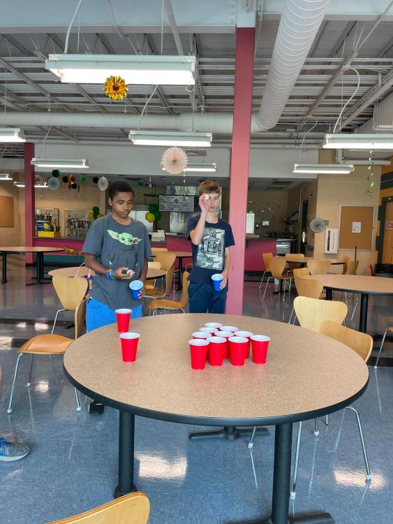 students playing a game with a pingpong ball and cups