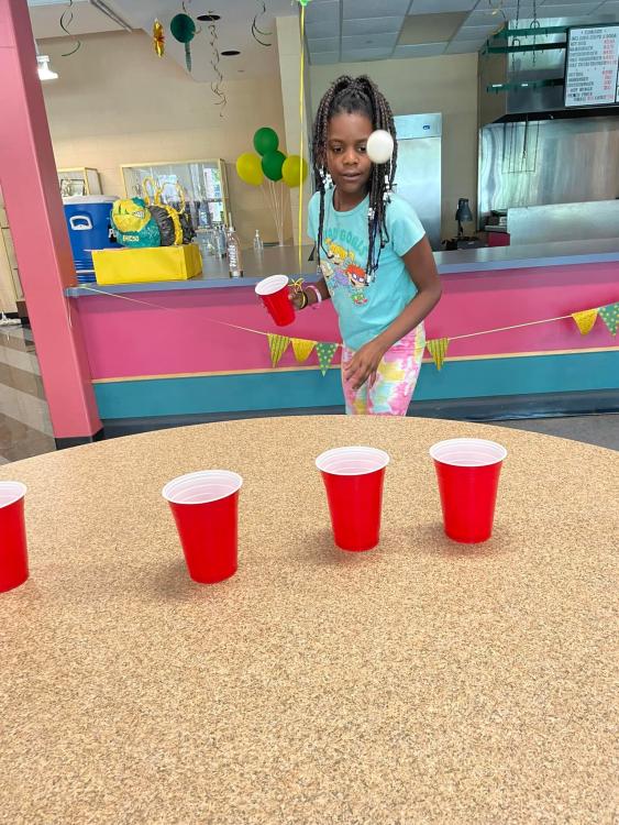 student playing game with pingpong ball and cups