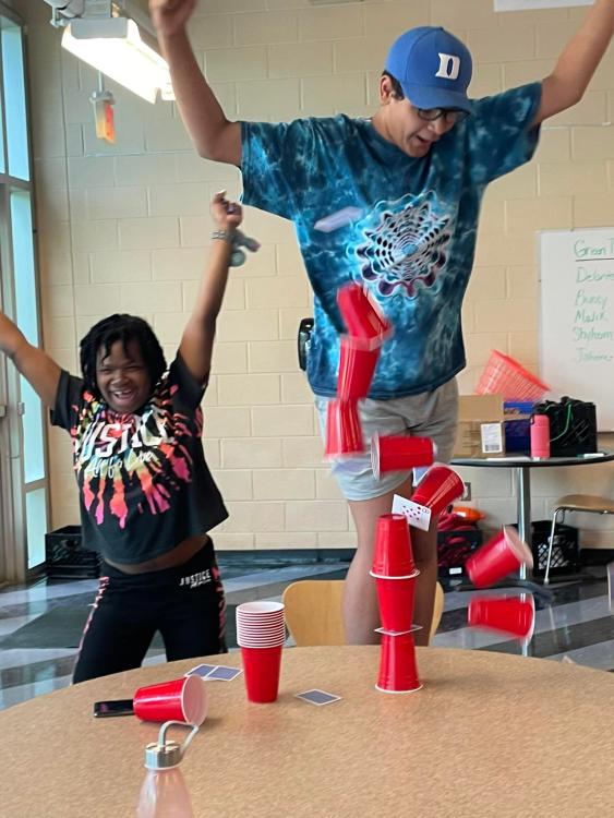 students cheering as stack of cups tumble