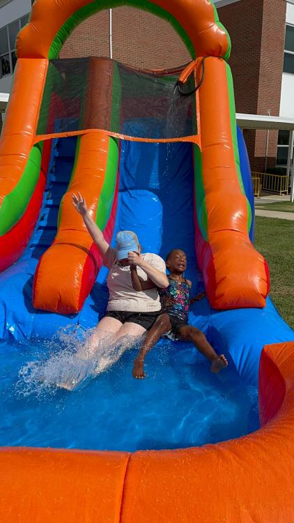 Natasha and student sliding down inflated water slide