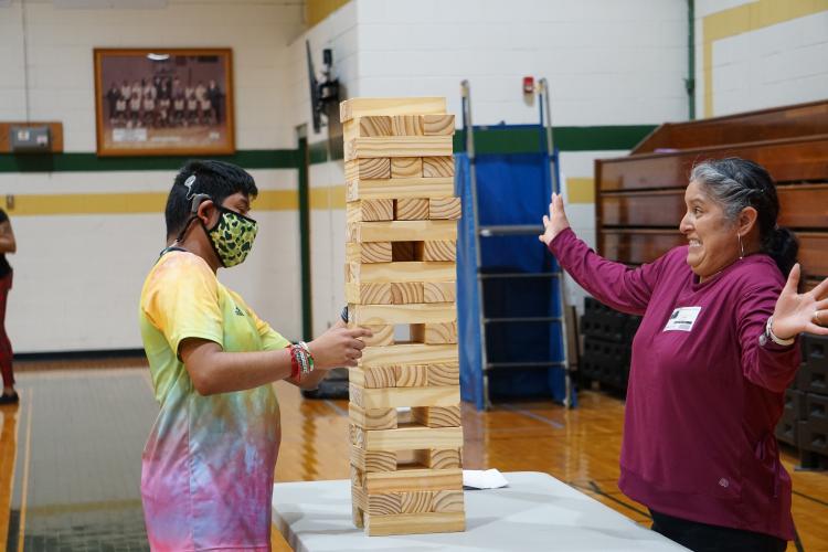 Student and parent playing Jenga with giant blocks.
