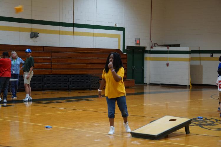 Student playing Corn Hole tossing a bean bag.
