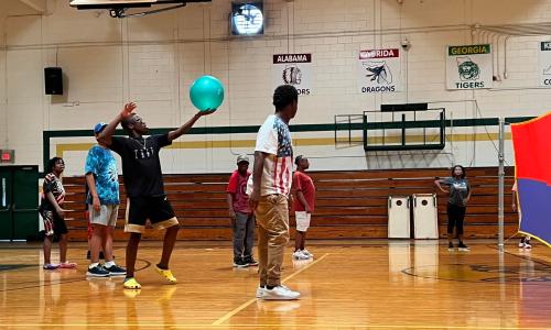 A student serves in a game of blind volleyball