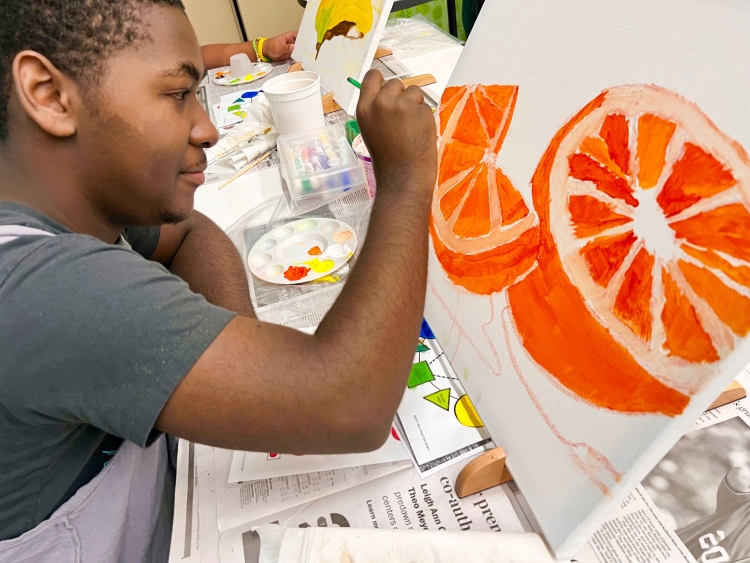 student painting oranges