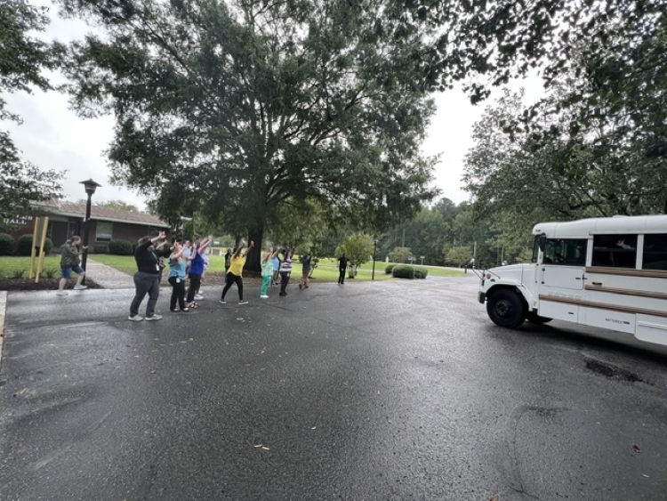 coed soccer team on bus staff waving goodbye