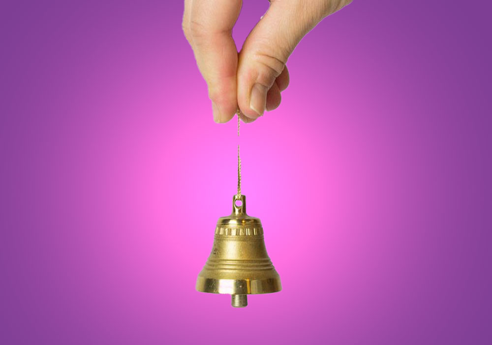 fingers holding string attached to tiny bell