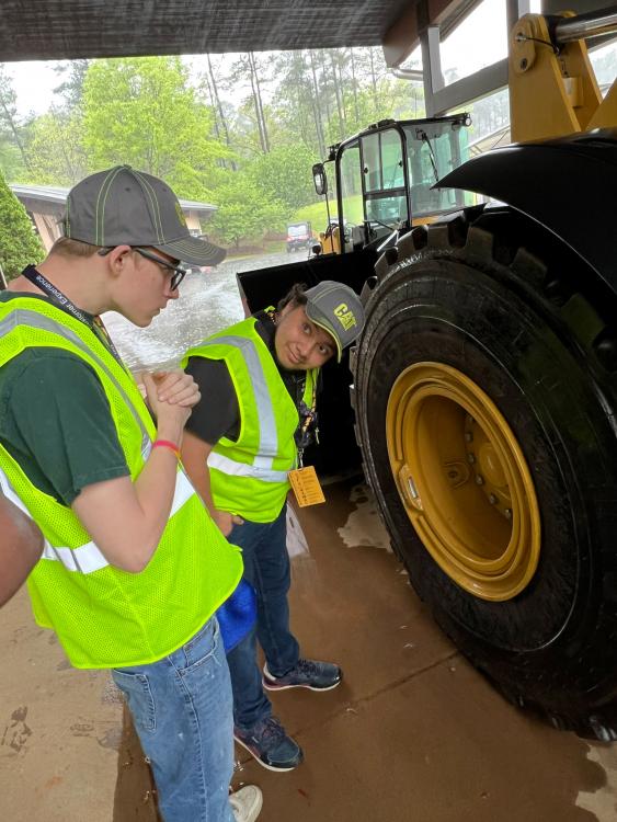 Students checking out the big tires on a Caterpillar wheel dozer