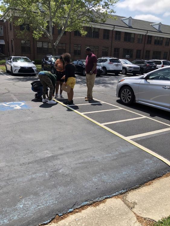 Students measuring the dimensions of a handicap parking space.