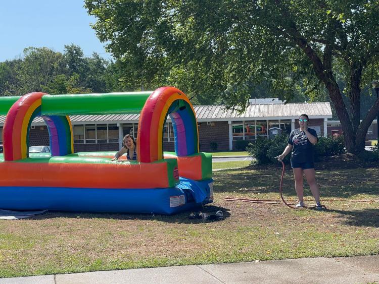 Staff with hose ready to spray student on inflated waterslide