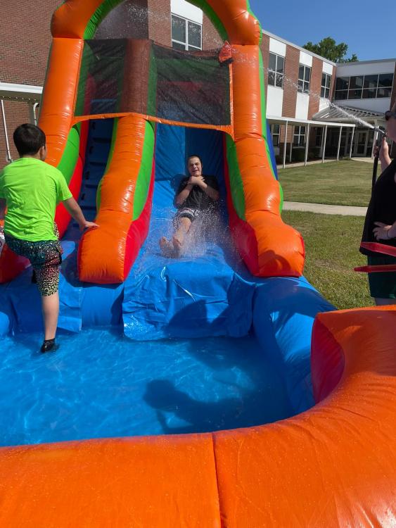 Student sliding down inflated water slide