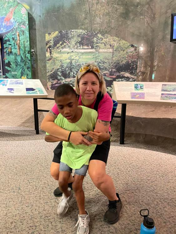 Heather holding a student at the NC Museum of Natural Sciences
