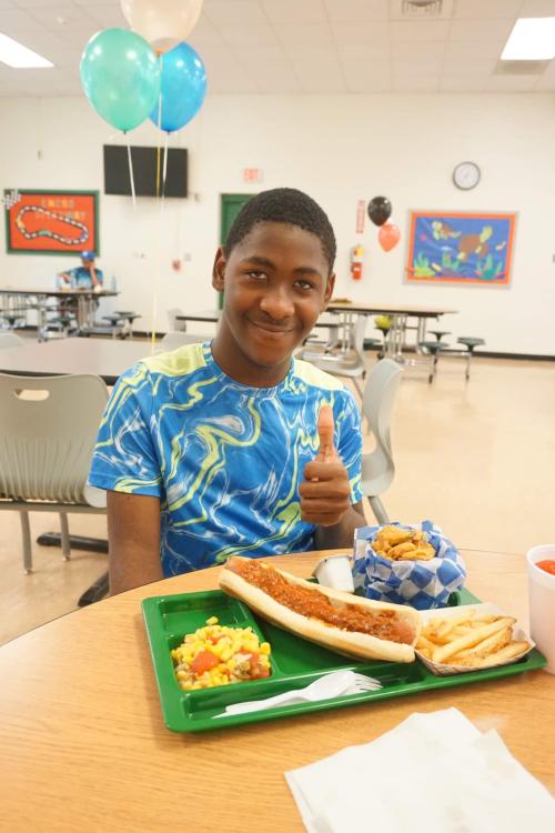 thumbs up from a student with a lunch tray