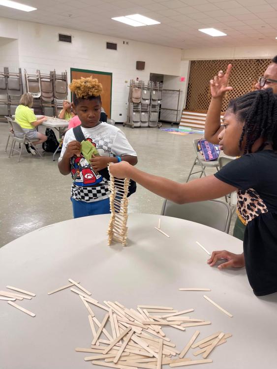 student stacking popsicle sticks