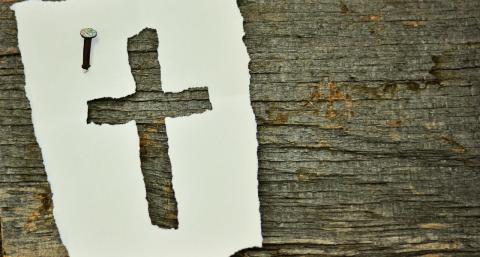 paper nailed to wood with a cross shape torn out of it